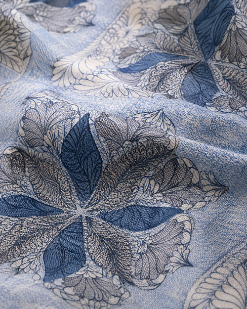 A close-up of a light blue fabric with a detailed floral pattern in navy blue and off-white.