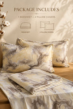 A bedding set displayed on a wooden bed frame with two pillowcases and a folded sheet, featuring a beige and gray marble pattern. Text at the top reads 'PACKAGE INCLUDES 1 BEDSHEET + 2 PILLOW COVERS' with simple line drawings.