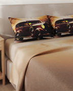 Two decorative throw pillows featuring a vintage car print, styled on a bed with beige bedding and a wooden side table in a bedroom setting.