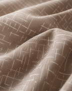 A close-up of draped fabric in a warm taupe-beige color with a subtle white geometric lattice pattern.