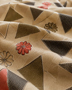 A close-up of a patterned fabric with a beige base, featuring geometric triangles in dark gray and olive green, and stylized flowers in red and gray.
